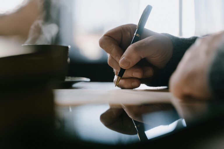 Focused adult hand writing with pen in a notebook, capturing creativity and concentration indoors.